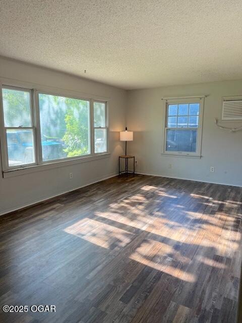 1705 S Walnut St, Pittsburg, KS 66762 - unfurnished room with a textured ceiling, a wall mounted AC, and dark wood finished floors