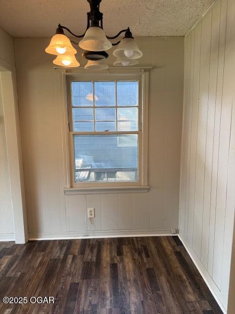 1705 S Walnut St, Pittsburg, KS 66762 - empty room with dark wood-type flooring, a chandelier, a textured ceiling, and wooden walls