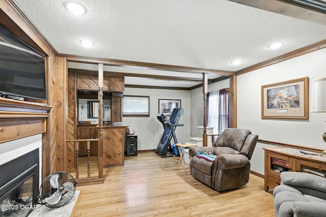 25327 Central Ave, Joplin, MO 64801 - living room featuring a textured ceiling, crown molding, a glass covered fireplace, light wood-type flooring, and recessed lighting