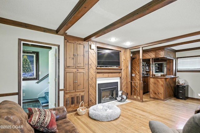 25327 Central Ave, Joplin, MO 64801 - living area featuring light wood-type flooring, a glass covered fireplace, beamed ceiling, crown molding, and stairs