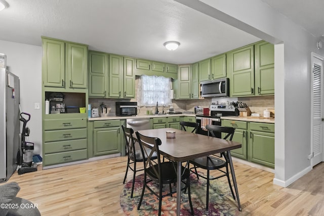 137 Lone Elm Dr, Carl Junction, MO 64834 - kitchen with appliances with stainless steel finishes, light wood-style flooring, green cabinetry, backsplash, and a textured ceiling
