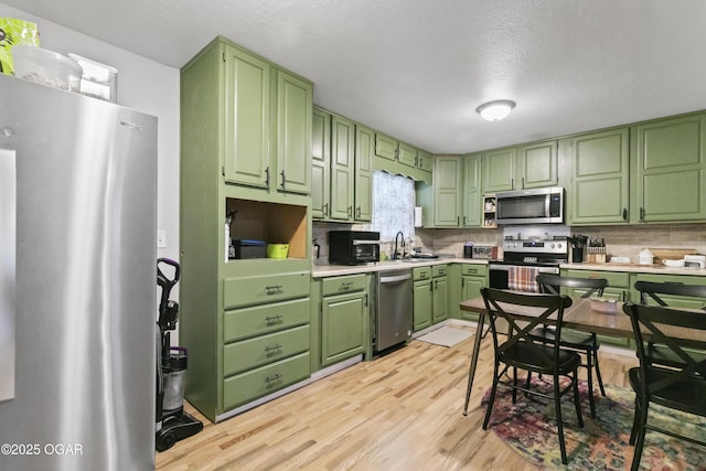 137 Lone Elm Dr, Carl Junction, MO 64834 - kitchen with stainless steel appliances, green cabinets, light wood finished floors, backsplash, and light countertops