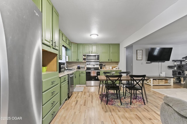 137 Lone Elm Dr, Carl Junction, MO 64834 - kitchen with stainless steel appliances, green cabinetry, light wood-style floors, light countertops, and tasteful backsplash