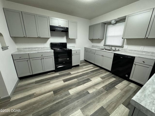 1003 Orchard St, Carthage, MO 64836 - kitchen featuring black appliances, under cabinet range hood, gray cabinetry, light countertops, and light wood finished floors