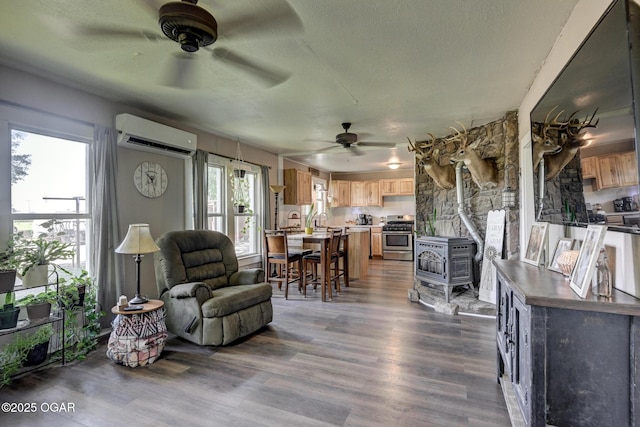 605 SE 10th Ln, Lamar, MO 64759 - living area featuring a wood stove, a ceiling fan, a wall mounted AC, dark wood-style floors, and a textured ceiling