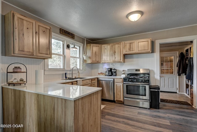 605 SE 10th Ln, Lamar, MO 64759 - kitchen with stainless steel appliances, light brown cabinetry, light countertops, a peninsula, and dark wood-type flooring