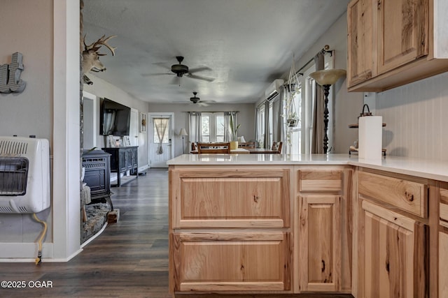 605 SE 10th Ln, Lamar, MO 64759 - kitchen featuring heating unit, a wood stove, a peninsula, dark wood finished floors, and a ceiling fan