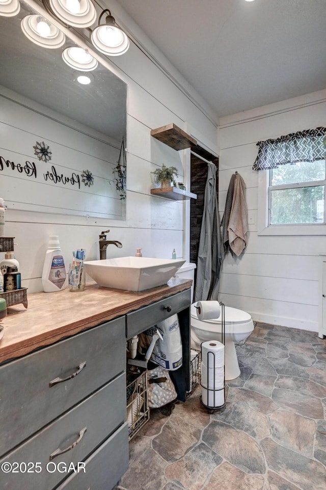 605 SE 10th Ln, Lamar, MO 64759 - bathroom featuring stone finish flooring, vanity, a shower with shower curtain, and wooden walls