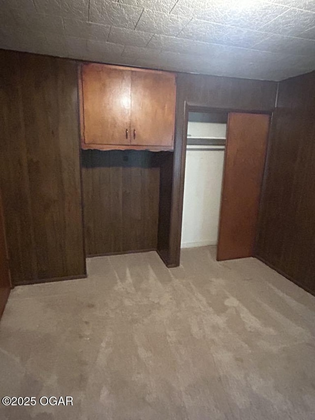 419 Depot St, Oswego, KS 67356 - unfurnished bedroom with wooden walls, light colored carpet, and a closet