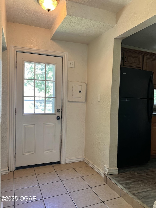 821 New Hampshire Ave, Joplin, MO 64801 - doorway to outside featuring a textured wall, a textured ceiling, light tile patterned floors, and electric panel