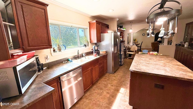 4950 SE 118th St, Galena, KS 66739 - kitchen featuring appliances with stainless steel finishes, light tile patterned flooring, ornamental molding, hanging light fixtures, and brown cabinetry