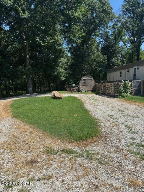 8305A Ivory Rd, Reeds, MO 64859 - view of grassy yard with a storage shed, driveway, and view of wooded area