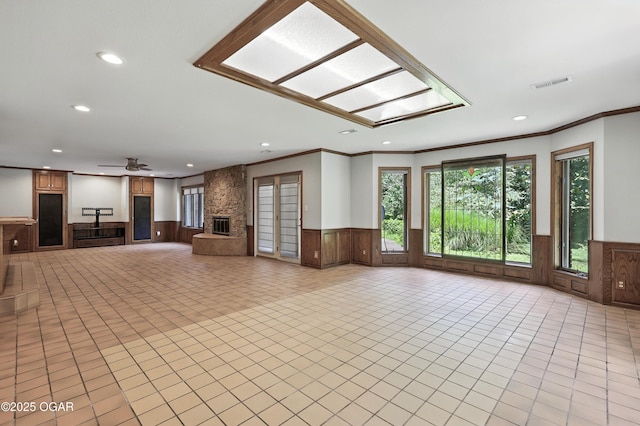 5623 Rivercrest Valley Dr, Joplin, MO 64804 - unfurnished living room featuring a wainscoted wall, recessed lighting, ornamental molding, ceiling fan, and a stone fireplace
