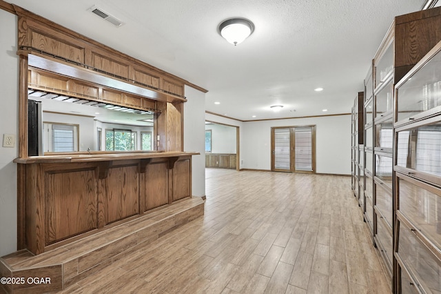 5623 Rivercrest Valley Dr, Joplin, MO 64804 - kitchen featuring light wood-style flooring, ornamental molding, open floor plan, a breakfast bar, and brown cabinetry