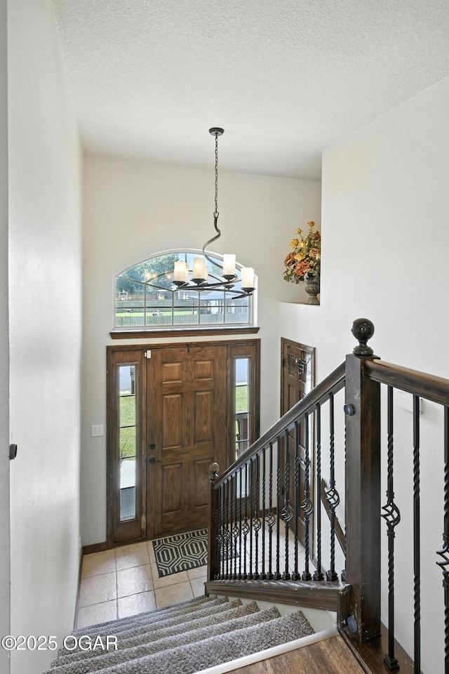 2256 N Greystone Sq, Webb City, MO 64870 - entrance foyer featuring a chandelier, plenty of natural light, a textured ceiling, tile patterned flooring, and a high ceiling
