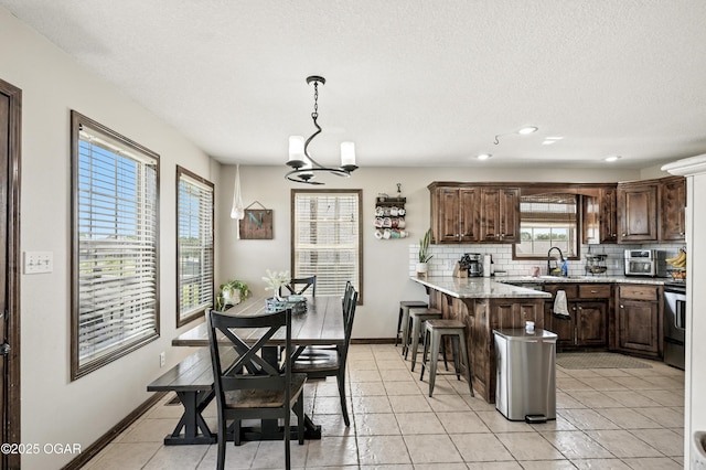 2256 N Greystone Sq, Webb City, MO 64870 - kitchen with backsplash, a kitchen breakfast bar, stainless steel electric stove, a peninsula, and dark brown cabinetry