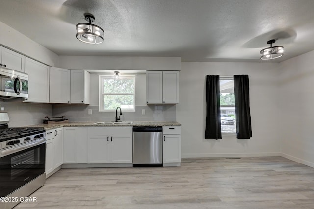 233 Timber Ln, Carl Junction, MO 64834 - kitchen with appliances with stainless steel finishes, decorative backsplash, light wood finished floors, light stone counters, and a textured ceiling