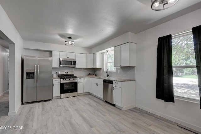 233 Timber Ln, Carl Junction, MO 64834 - kitchen with stainless steel appliances, plenty of natural light, light stone countertops, and light wood-style floors