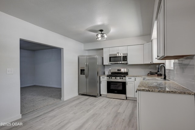 233 Timber Ln, Carl Junction, MO 64834 - kitchen with appliances with stainless steel finishes, stone counters, light wood finished floors, and white cabinetry