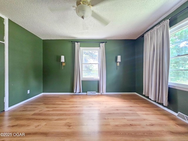 2507 N Ozark Ave, Joplin, MO 64801 - spare room featuring a textured ceiling, plenty of natural light, wood finished floors, and a ceiling fan