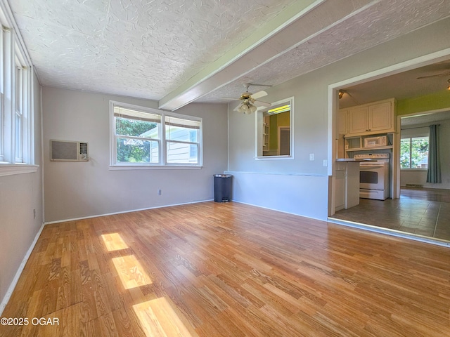 2507 N Ozark Ave, Joplin, MO 64801 - unfurnished living room with a ceiling fan, a textured ceiling, light wood-type flooring, healthy amount of natural light, and a wall unit AC