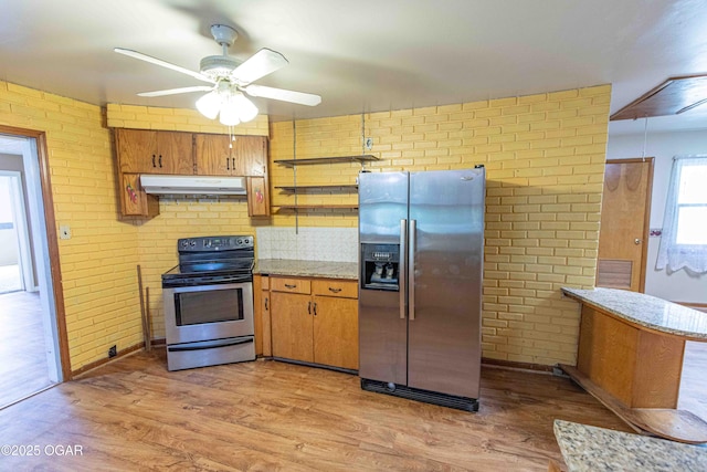 400 Broadway St, Lamar, MO 64759 - kitchen featuring stainless steel appliances, under cabinet range hood, ceiling fan, light wood finished floors, and brick wall