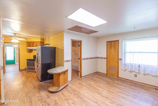400 Broadway St, Lamar, MO 64759 - kitchen featuring appliances with stainless steel finishes, light wood-type flooring, under cabinet range hood, light countertops, and a skylight