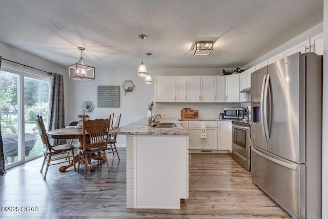715 Wilson St, Webb City, MO 64870 - kitchen with appliances with stainless steel finishes, a peninsula, white cabinets, tasteful backsplash, and a textured ceiling