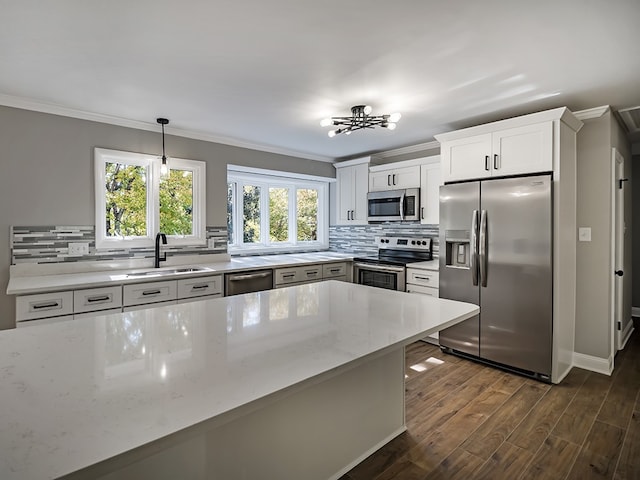 kitchen with pendant lighting, sink, white cabinets, ornamental molding, and stainless steel appliances