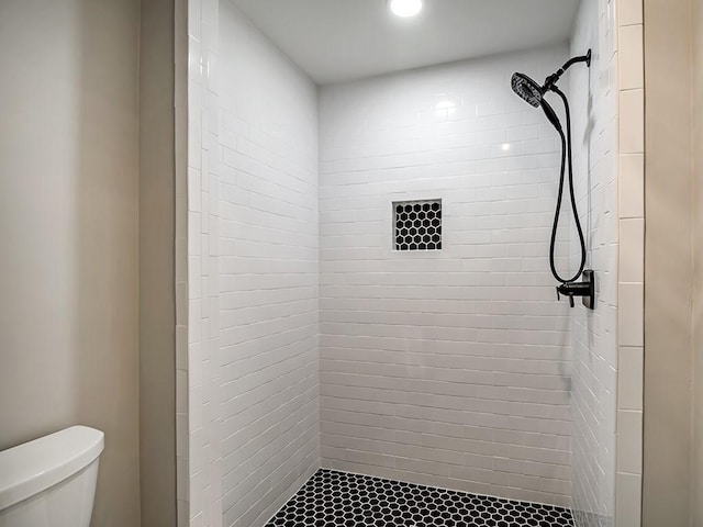 bathroom with toilet and a tile shower