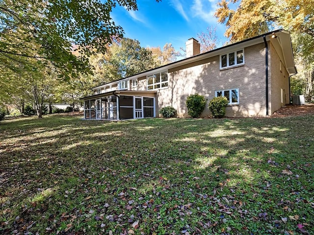 rear view of property featuring central AC unit, a yard, and a sunroom