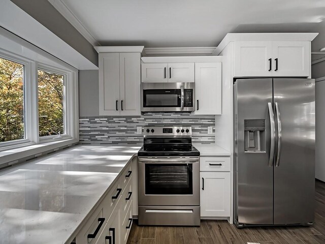 kitchen featuring crown molding, white cabinetry, stainless steel appliances, dark hardwood / wood-style floors, and decorative backsplash