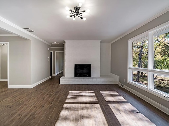 unfurnished living room featuring a brick fireplace, crown molding, dark hardwood / wood-style floors, and a chandelier