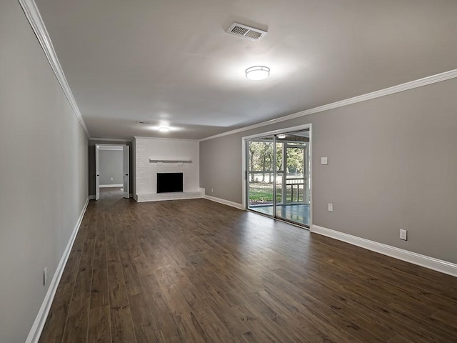 unfurnished living room featuring a brick fireplace, crown molding, and dark wood-type flooring