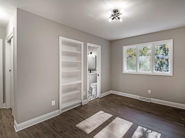 unfurnished bedroom with ensuite bath and dark hardwood / wood-style floors