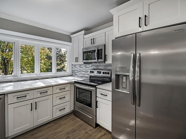 kitchen featuring ornamental molding, dark hardwood / wood-style flooring, stainless steel appliances, decorative backsplash, and white cabinets