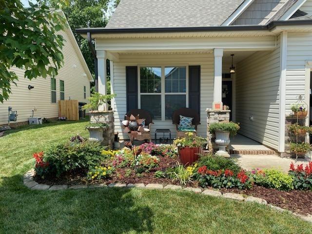 view of exterior entry featuring covered porch and a lawn