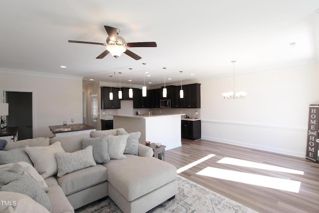 living room with ornamental molding, wood-type flooring, and ceiling fan with notable chandelier