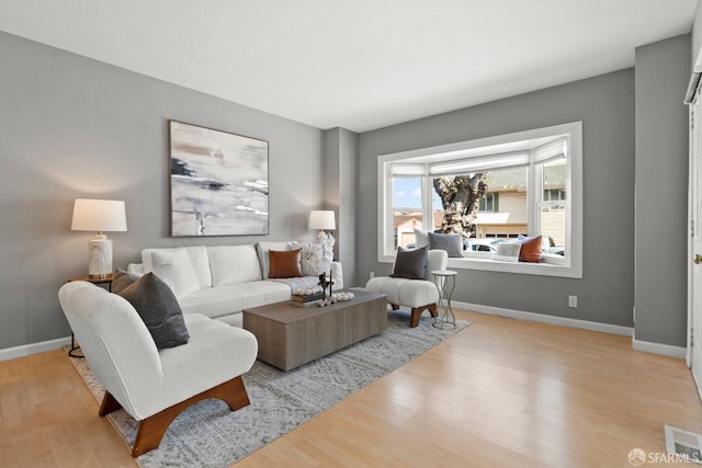 living area with baseboards, visible vents, and wood finished floors