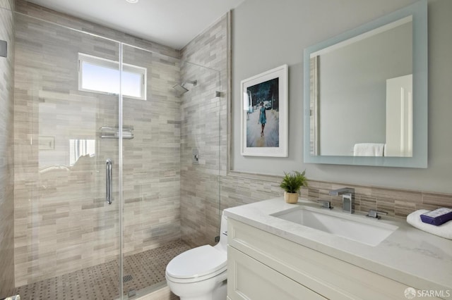 bathroom with walk in shower, vanity, toilet, and tile walls