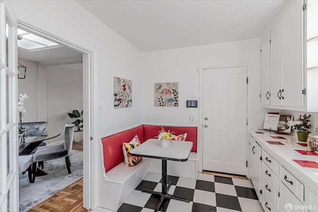 kitchen featuring breakfast area, a skylight, white cabinets, light floors, and tile counters