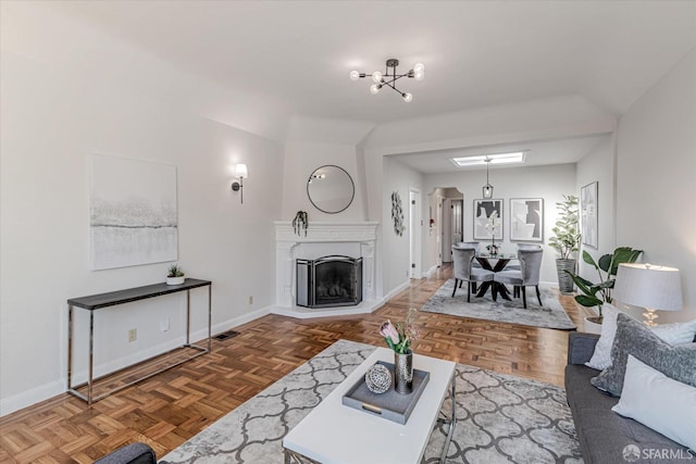 living room featuring an inviting chandelier, baseboards, visible vents, and a fireplace with raised hearth