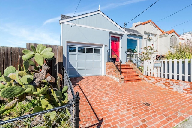 view of front of home with decorative driveway, fence, and a garage