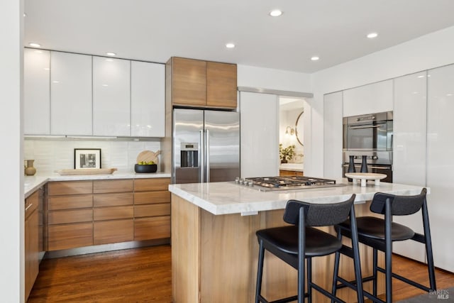1837 Centro W St, Tiburon, CA 94920 - kitchen featuring a breakfast bar, modern cabinets, dark wood finished floors, appliances with stainless steel finishes, and white cabinetry