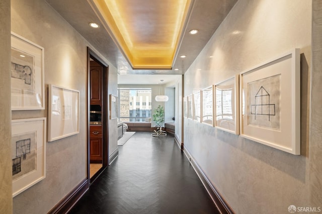 hall with dark parquet floors and a tray ceiling