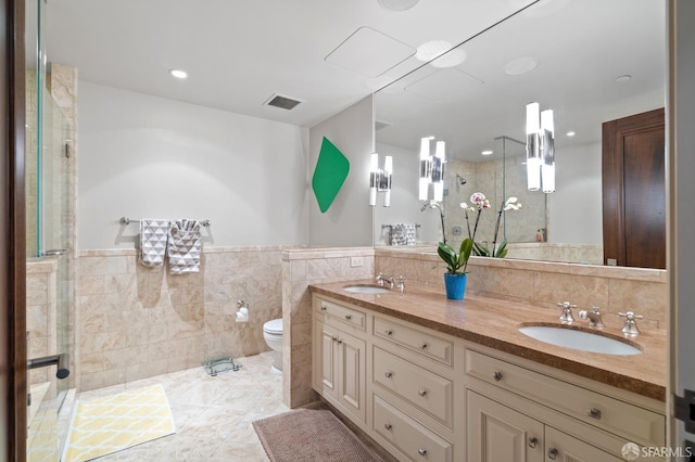 bathroom featuring toilet, vanity, an enclosed shower, and tile walls