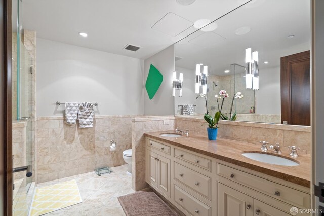 765 Market St Unit 28D, San Francisco, CA 94103 - bathroom with tile walls, a shower stall, toilet, double vanity, and a wainscoted wall