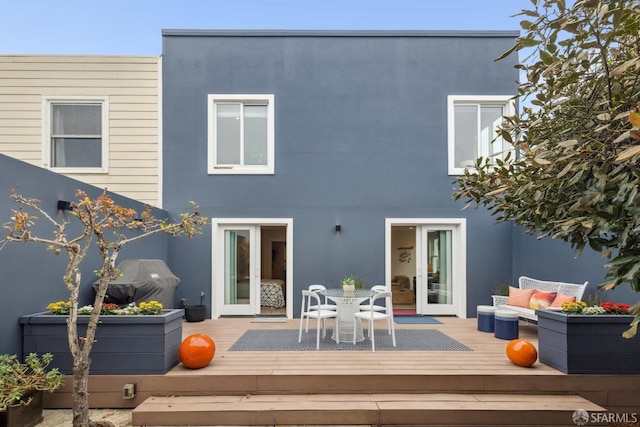 back of house with a deck, outdoor dining space, and stucco siding