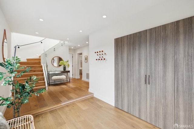 hallway featuring stairs, baseboards, wood finished floors, and recessed lighting