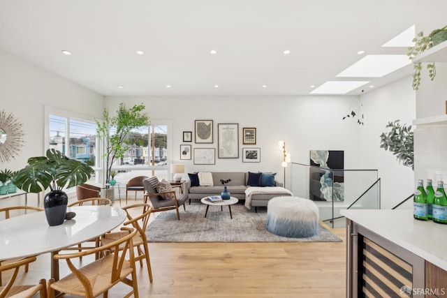 living room with beverage cooler, a skylight, light wood-style flooring, and recessed lighting